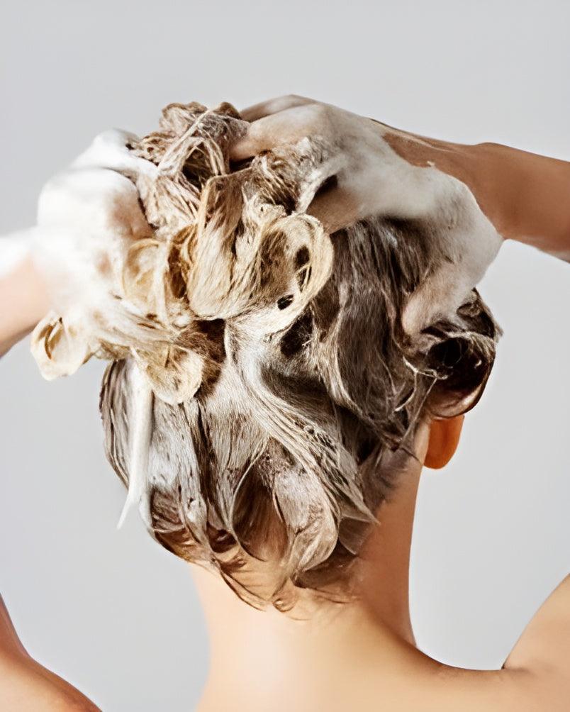 Person washing hair with Eclat Soin Sensitive Scalp Shampoo for a gentle cleansing experience